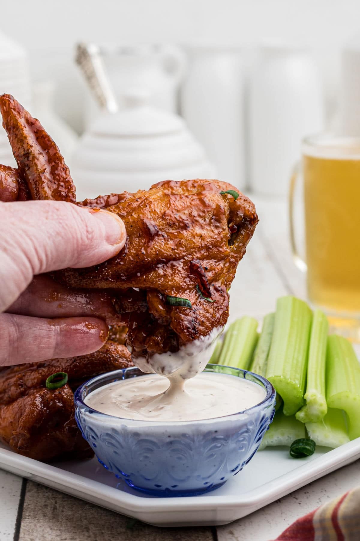 Chicken wings being dipped into ranch dressing, showcasing the crispy exterior after reheating in an air fryer.
