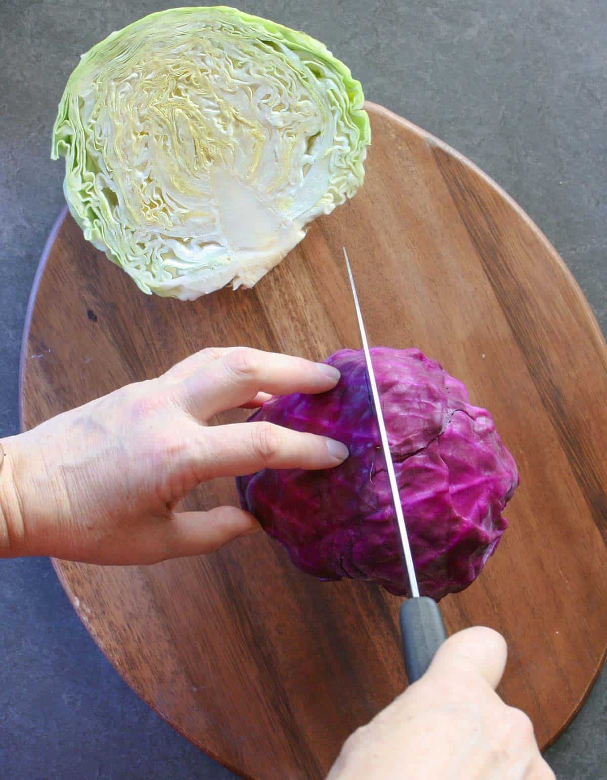 Cutting a red cabbage in half on a wooden cutting board