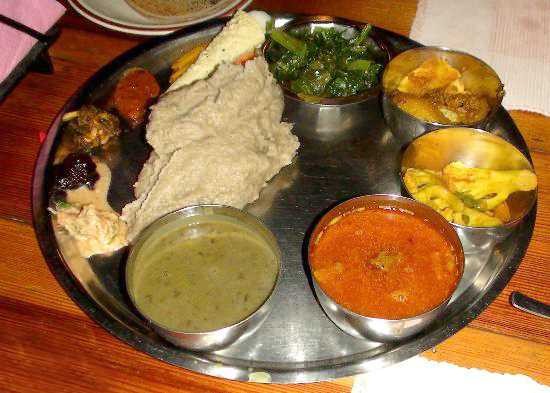A plate of Dhindo or Dhido Thali featuring a thick porridge prepared by boiling stone-ground cornmeal