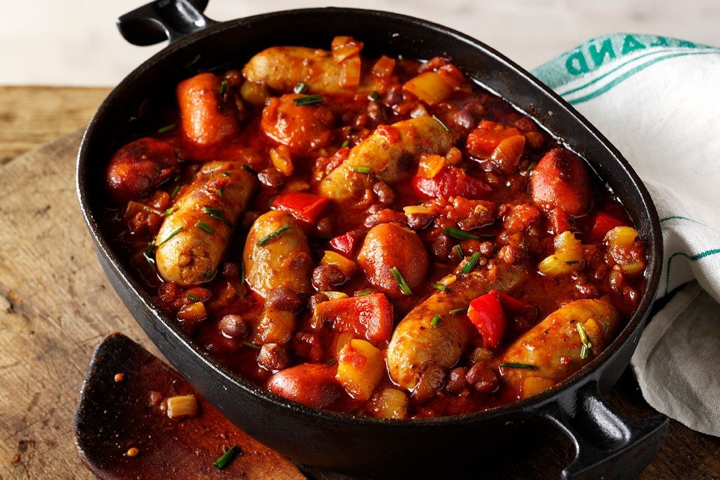 Sausages, yellow and red peppers and chopped tomatoes in a pan