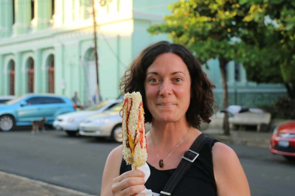Woman holding corn with cheese and sauces