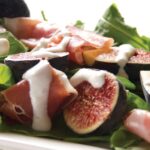 Speck and cheese board featuring Gruyère and Parmesan, paired with figs and apples
