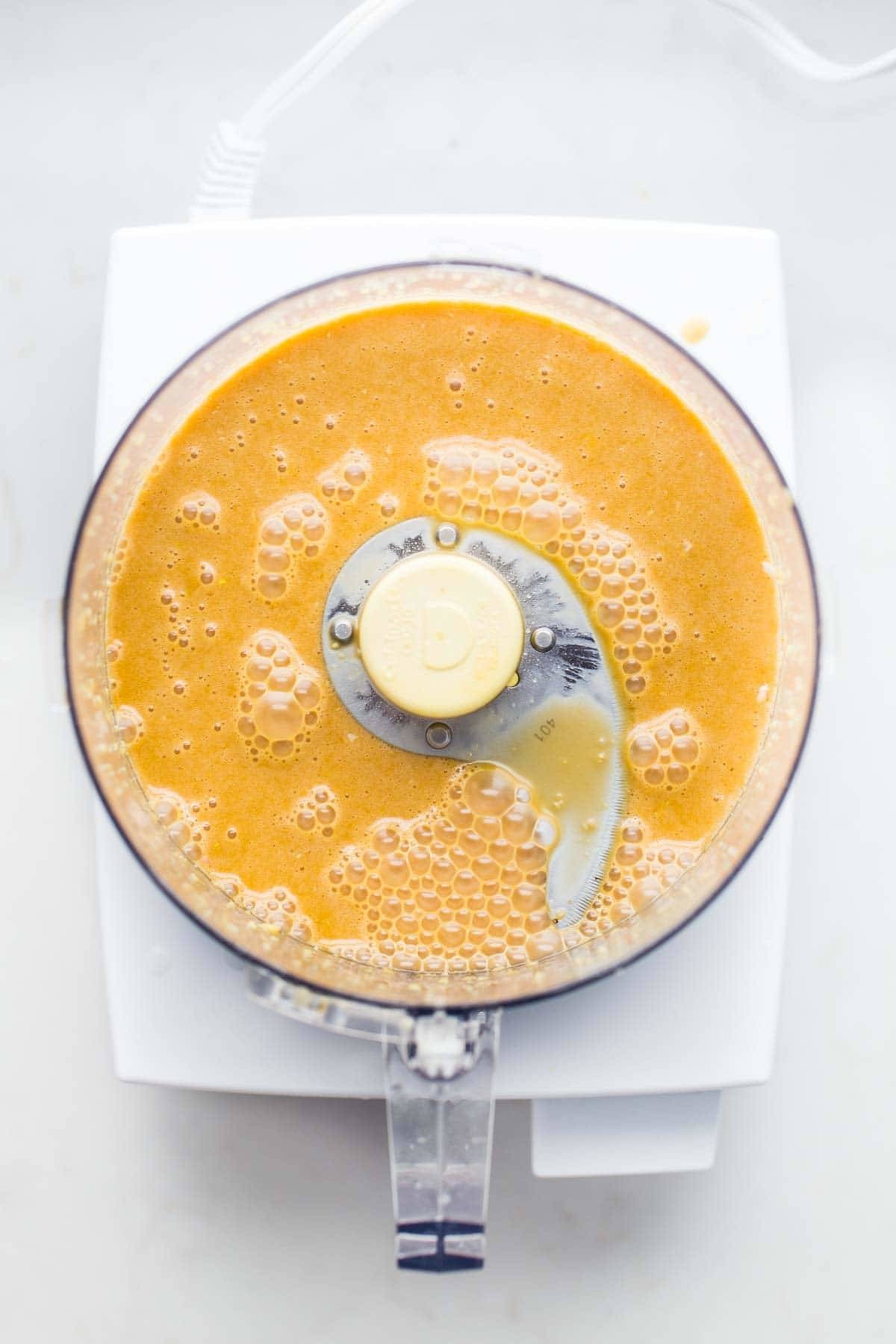 Homemade salad dressing being made in a food processor, emphasizing the appliance's role in creating flavorful dressings.