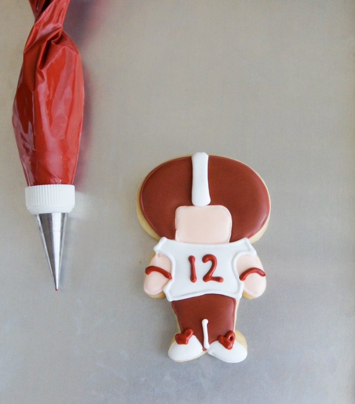 Cookies decorated with maroon icing details using a fine piping tip