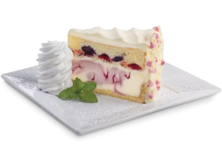 Strawberry cheesecake slice on a plate with whipped cream.