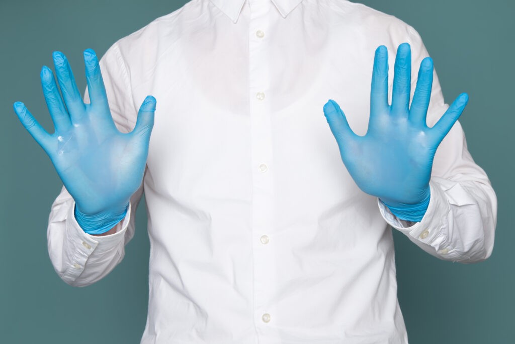 A worker wearing blue nitrile gloves while preparing food