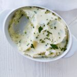 Oval dish of garlic mashed potatoes with a serving removed