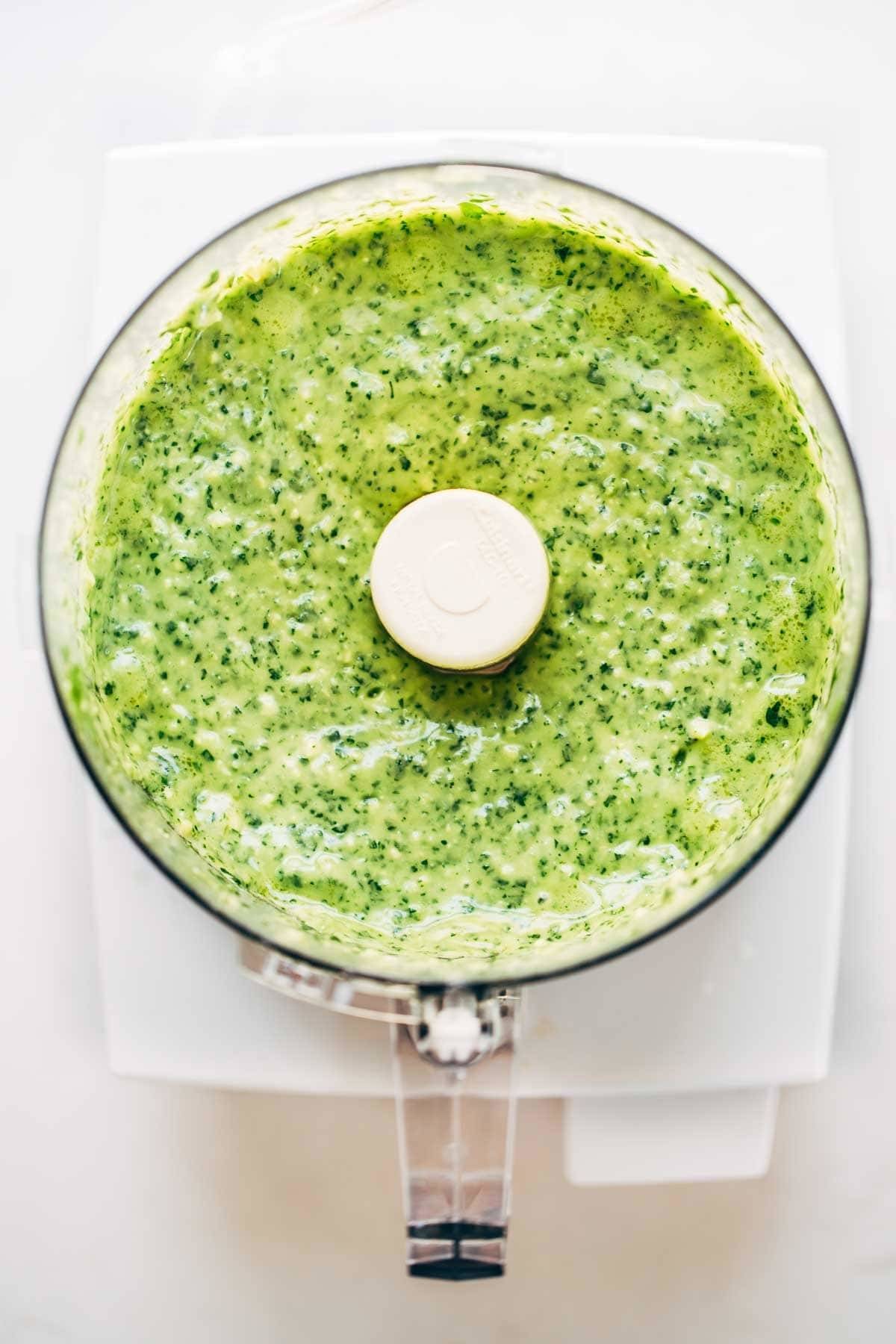 Bright green sauce being made in a food processor, demonstrating its versatility in creating flavorful condiments.