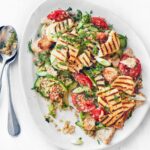 Halloumi and quinoa fattoush plated alongside silver spoons.