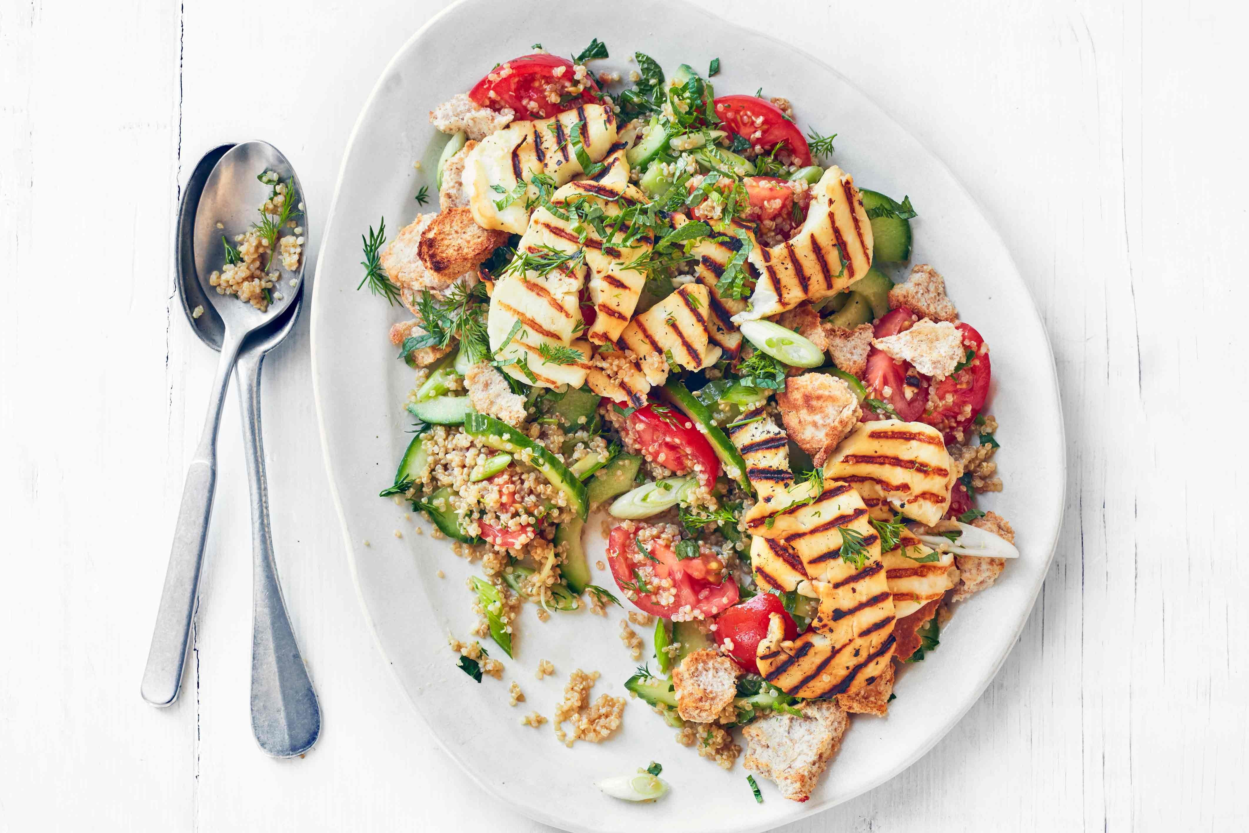 Halloumi and quinoa fattoush plated alongside silver spoons.
