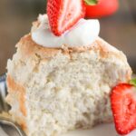 Close-up of a slice of sugar-free angel food cake on a plate with fresh berries