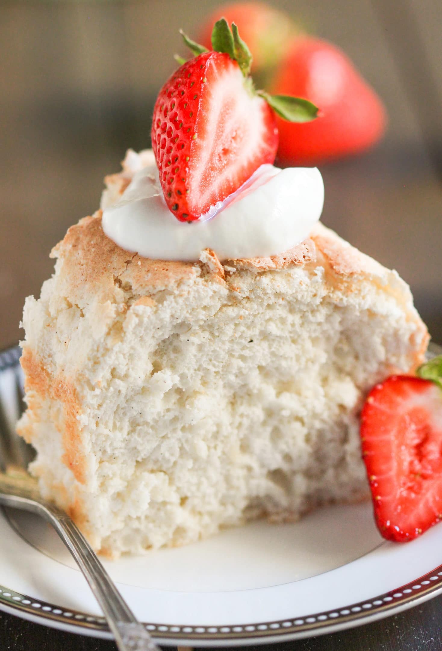 Close-up of a slice of sugar-free angel food cake on a plate with fresh berries