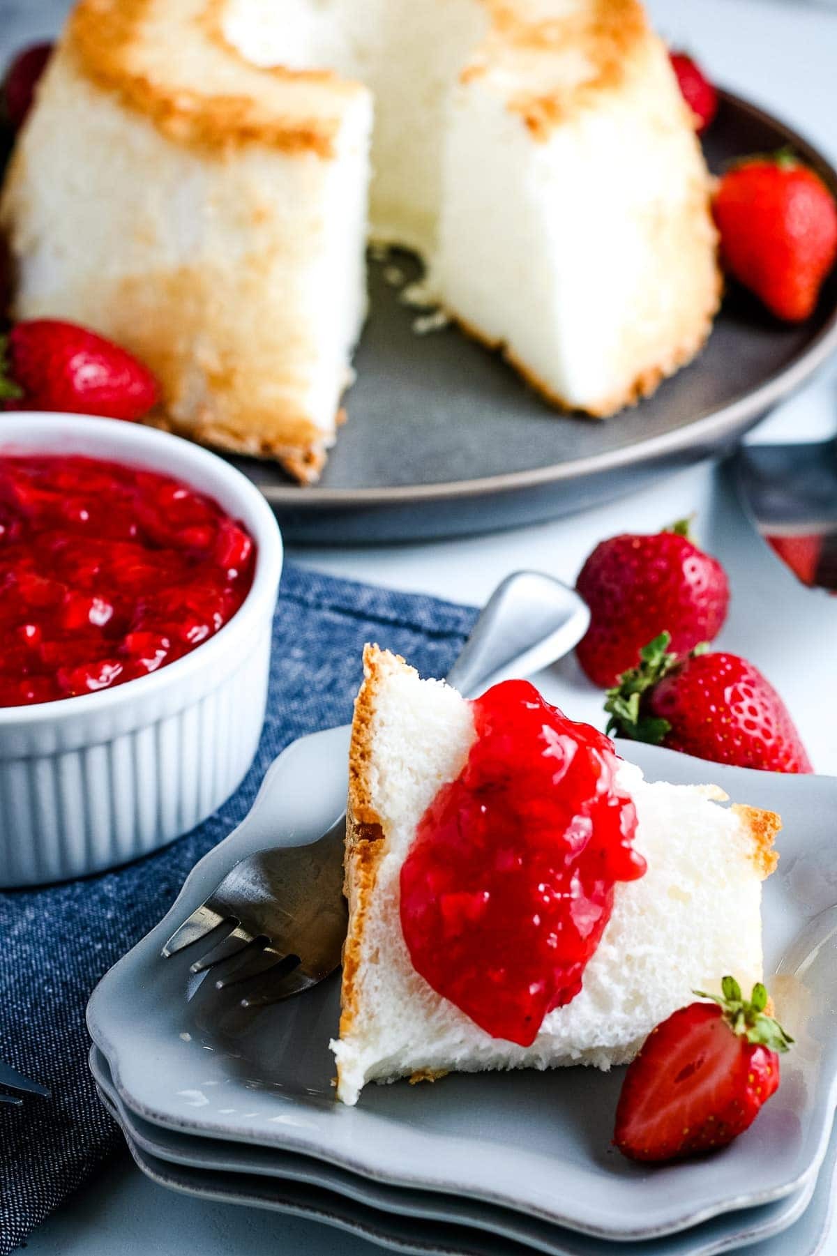 Freshly made strawberry sauce being spooned onto a slice of angel food cake, showcasing its vibrant color and perfect consistency