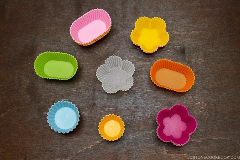 Colorful silicone cups used to divide different food items within a bento box.