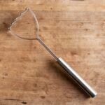 Wooden background with silver potato masher on