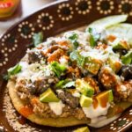 Traditional Mexican Huaraches, showcasing the oblong masa base topped with beans, meat, cheese, and salsa, a staple of Mexican street food.