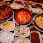 A lavish Turkish breakfast spread featuring cheese, bread, jams, eggs, and sucuk