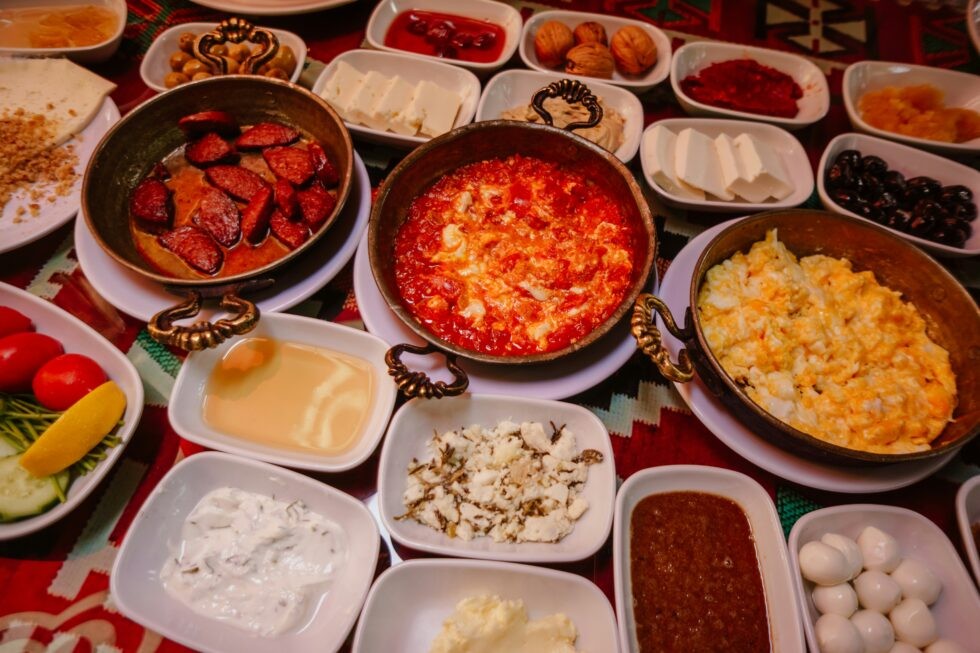 A lavish Turkish breakfast spread featuring cheese, bread, jams, eggs, and sucuk