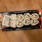 Selection of sushi rolls on display in a refrigerated case at Whole Foods Market, highlighting the pre-made nature and variety available.
