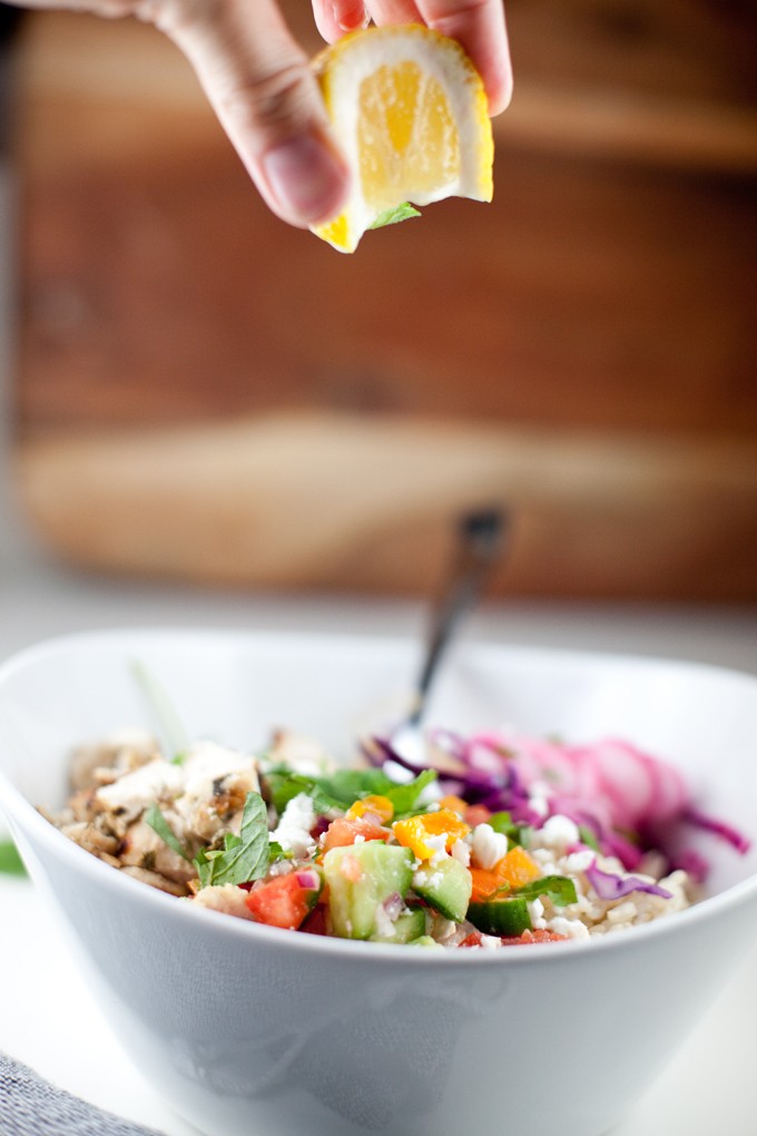 Image of someone squeezing fresh lemon onto a copycat Cava Mediterranean Grain bowl, highlighting the zest and freshness of the ingredients
