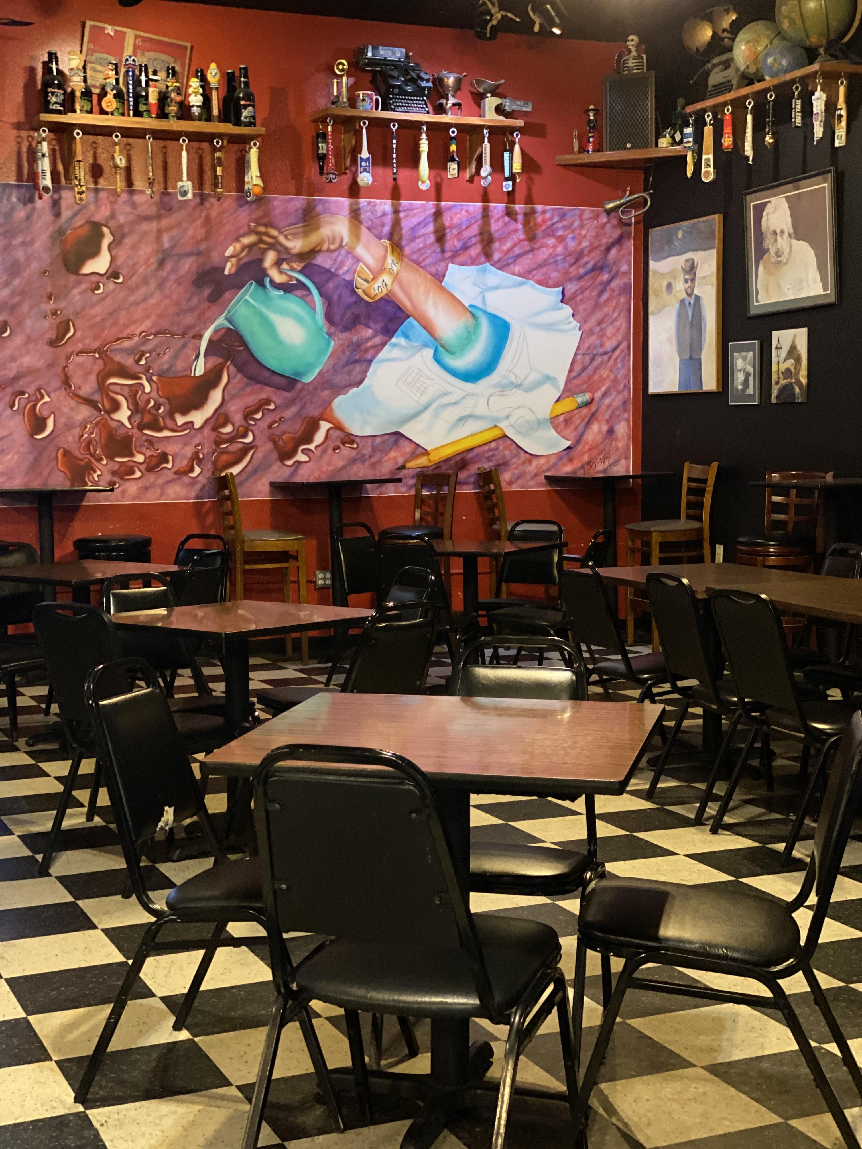 Dining area of Logon Cafe with mural of hand pouring wine from pitcher, creating a lively atmosphere
