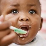 Baby with spoon in high chair