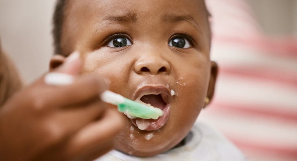 Baby with spoon in high chair