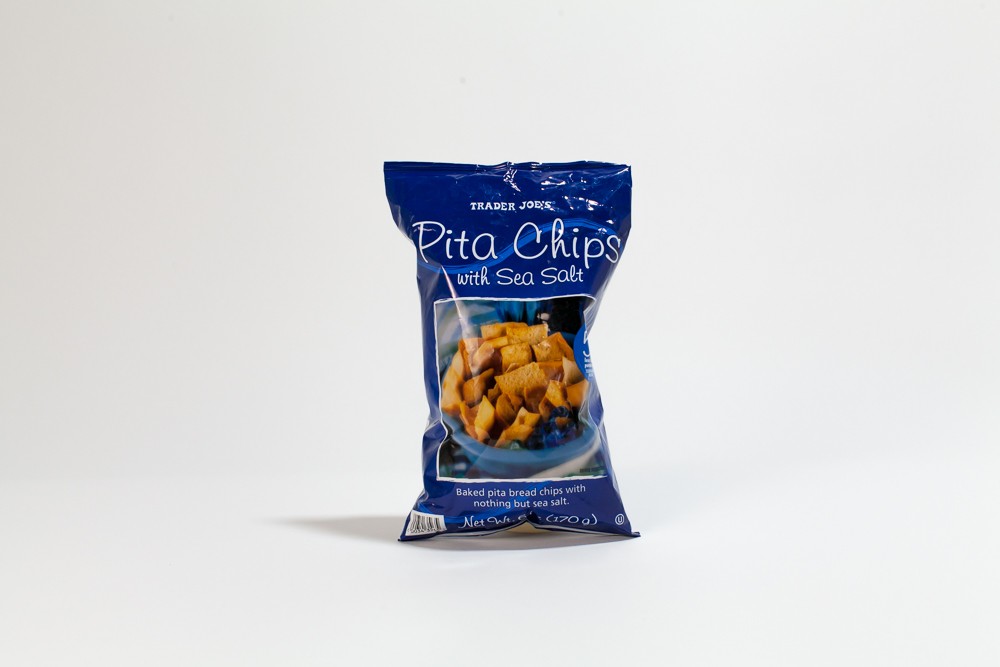 Close-up comparison of Trader Joe's and name-brand pita chips, highlighting identical ingredient lists.