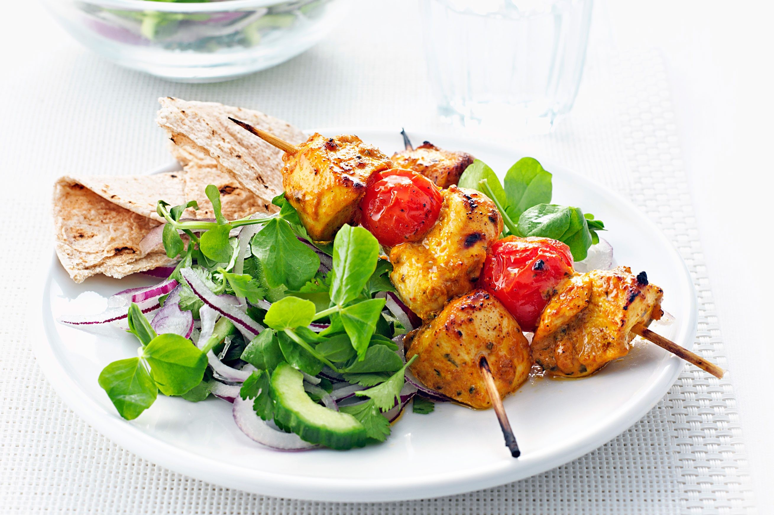 Chicken tikka skewers on a white plate