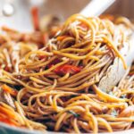 Tongs grabbing Lo Mein noodles