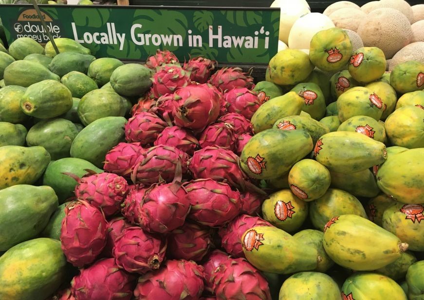 Piles of papaya and dragonfruit with a sign reading