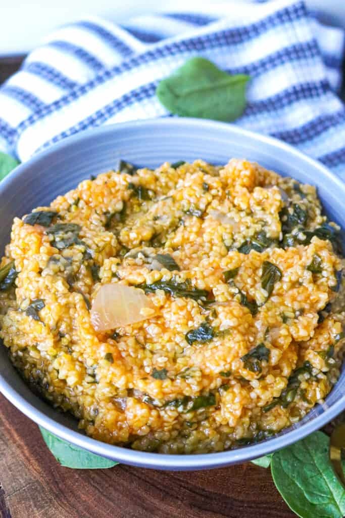 Mais Moulin mixed with spinach in blue plate with spinach leave around it