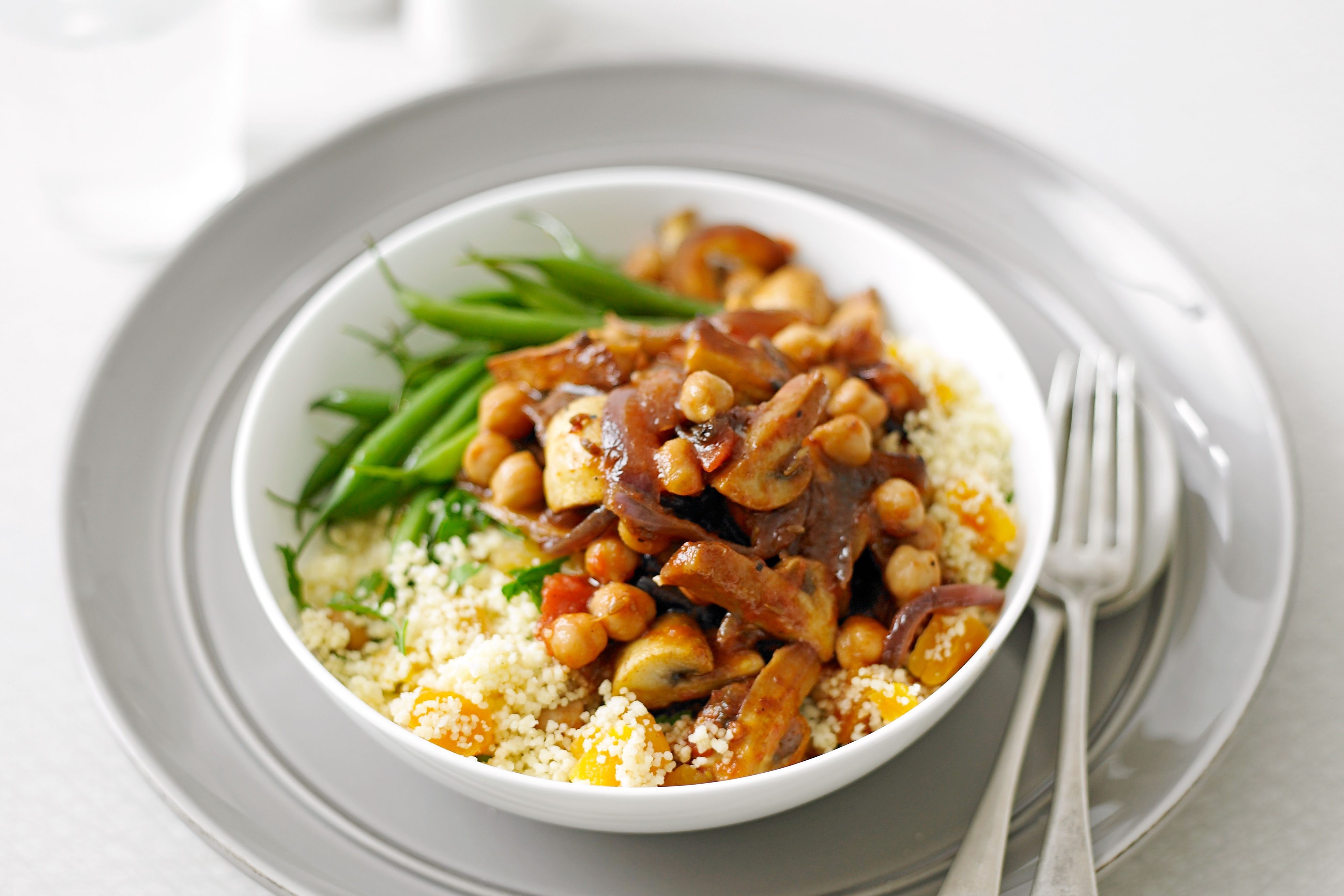 Moroccan mushroom tagine served on a bed of couscous with green beans, a vegetarian delight.