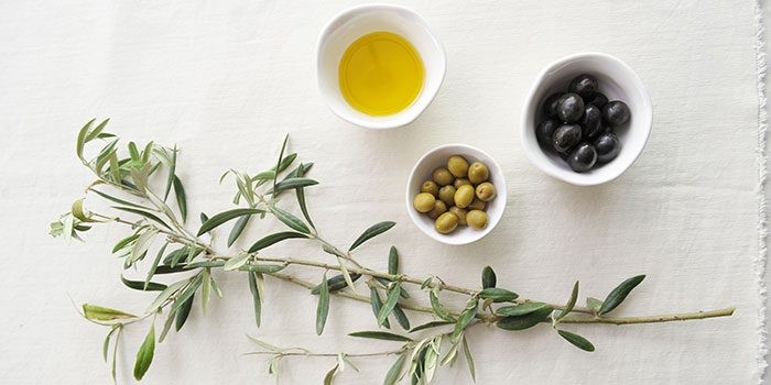 Close-up of fresh olives on a branch, showcasing their natural fruit form.