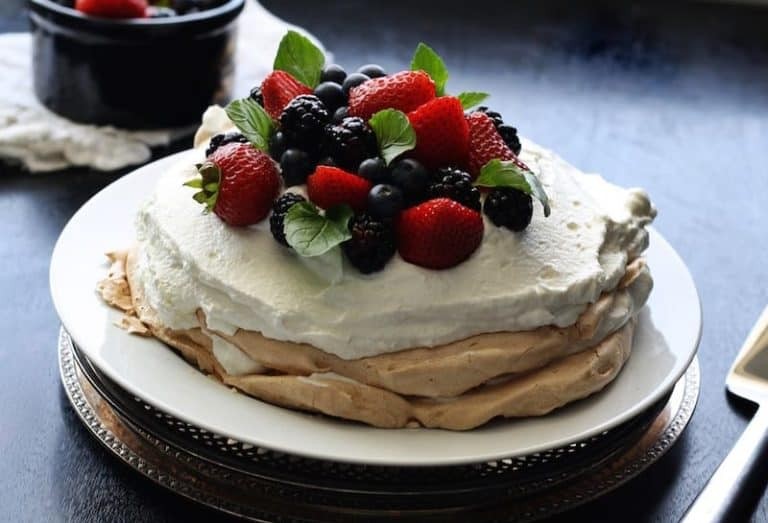 Pavlova, a meringue-based dessert topped with whipped cream and fresh fruit, showcasing its light and airy texture.