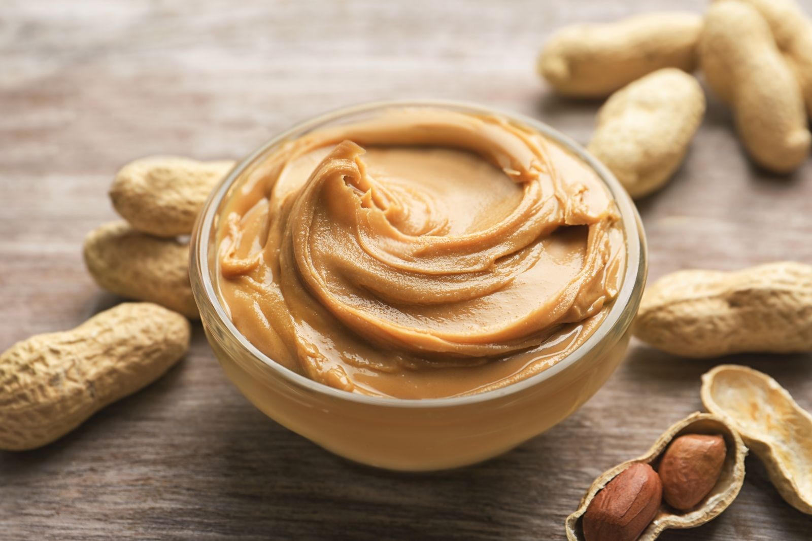 Creamy peanut butter on a knife, ready to be spread on a slice of whole-wheat bread, showcasing a healthy and nutritious snack option