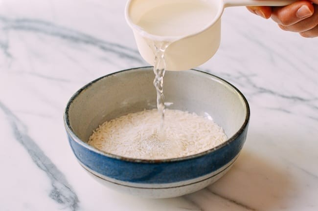 Adding water to rice in bowl for steaming, thewoksoflife.com