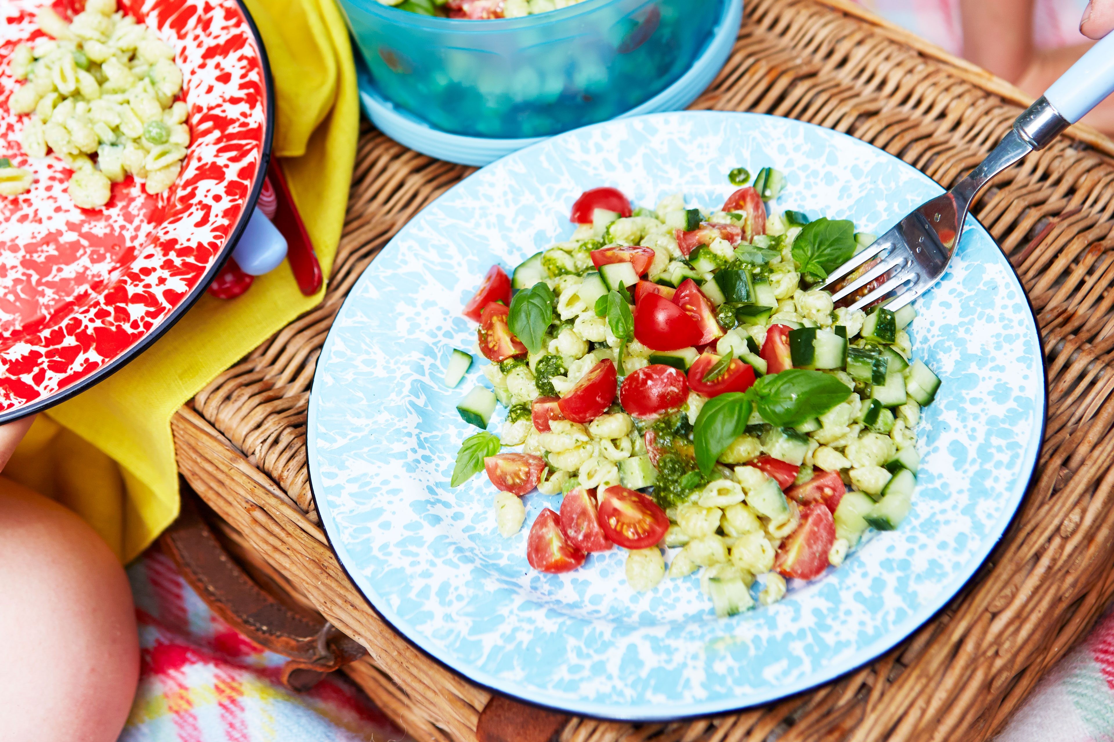 Pesto pasta salad with tomatoes and basil on a plate.