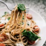 Close-up of a fork twirling spaghetti in a bowl, showcasing its texture and appeal