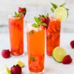 A glass pitcher filled with infused water, with slices of lemon and cucumber floating inside.