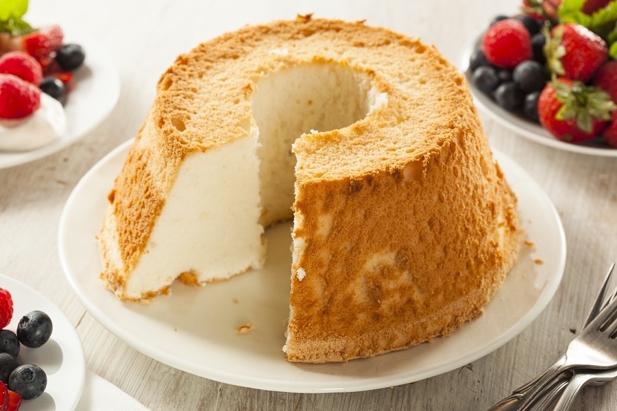 Close-up of angel food cake topped with fresh strawberries and a light dusting of powdered sugar, emphasizing the fresh and vibrant appeal.