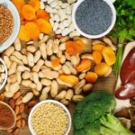 Variety of iron-rich foods, including apricots, peanuts, and broccoli, presented on a platter.