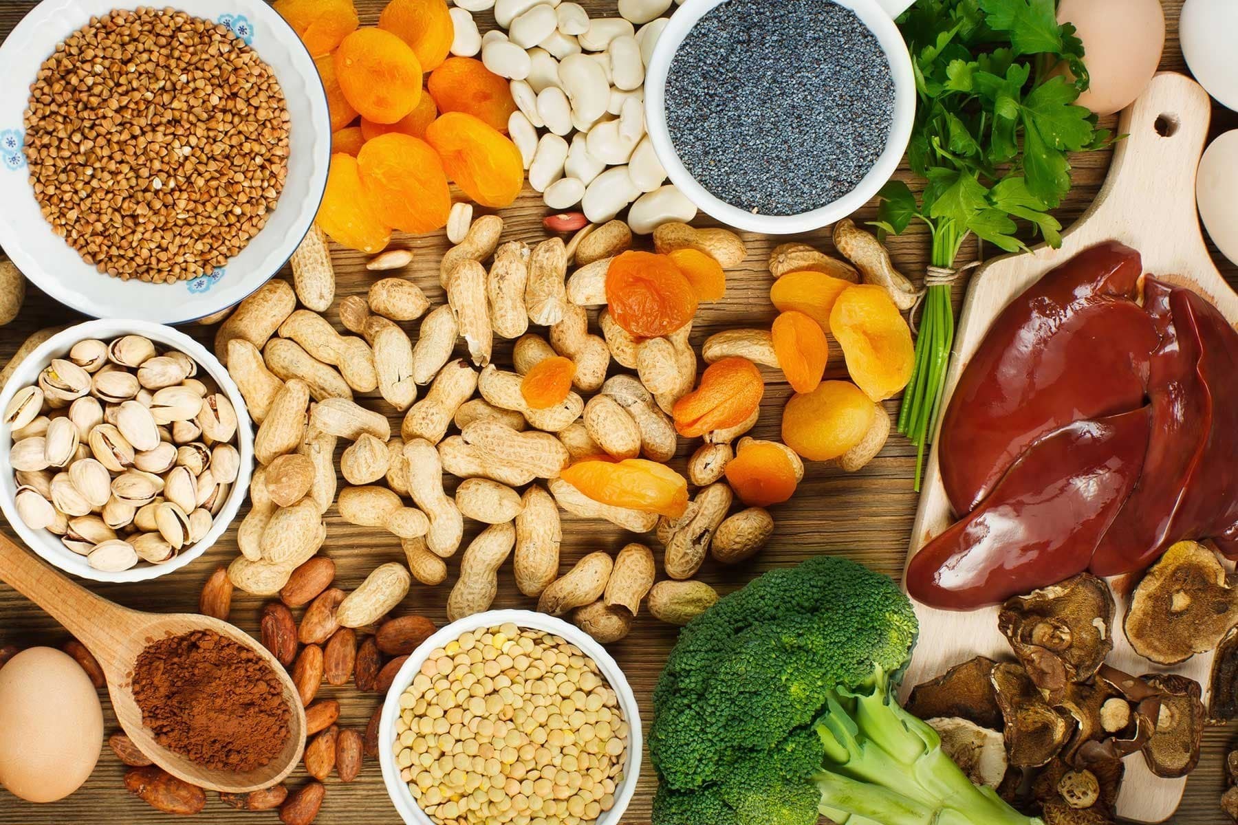 Variety of iron-rich foods, including apricots, peanuts, and broccoli, presented on a platter.