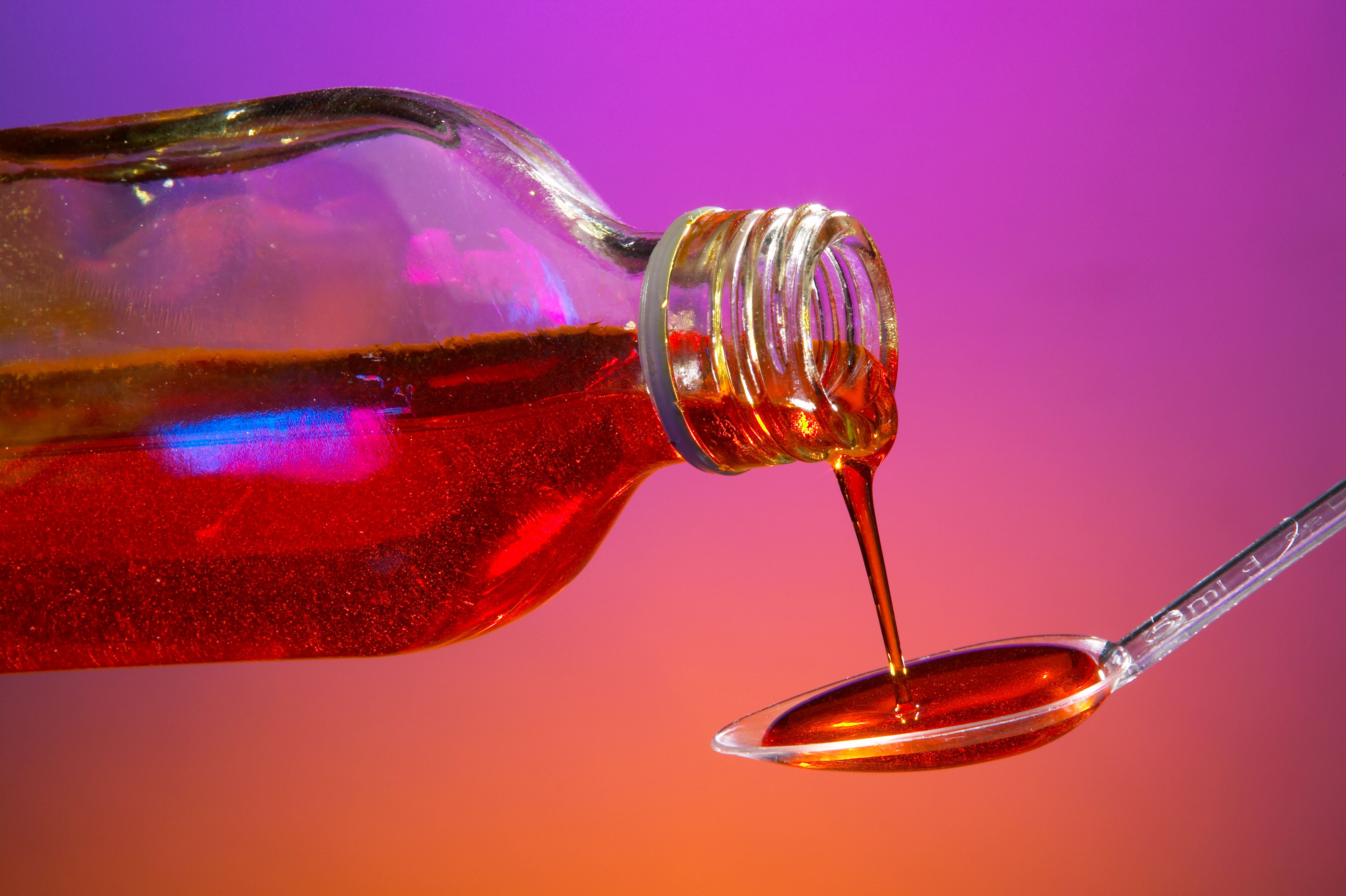 Red liquid medicine pouring =from bottle to spoon