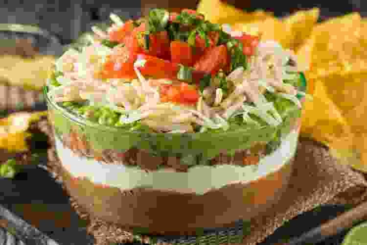 Seven layer dip is perfect for tailgate parties as it's easy to prepare and full of flavor