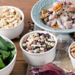 Close-up of assorted nuts, including hazelnuts, almonds, and pecans, displayed in a wooden bowl, showcasing their natural textures and colors