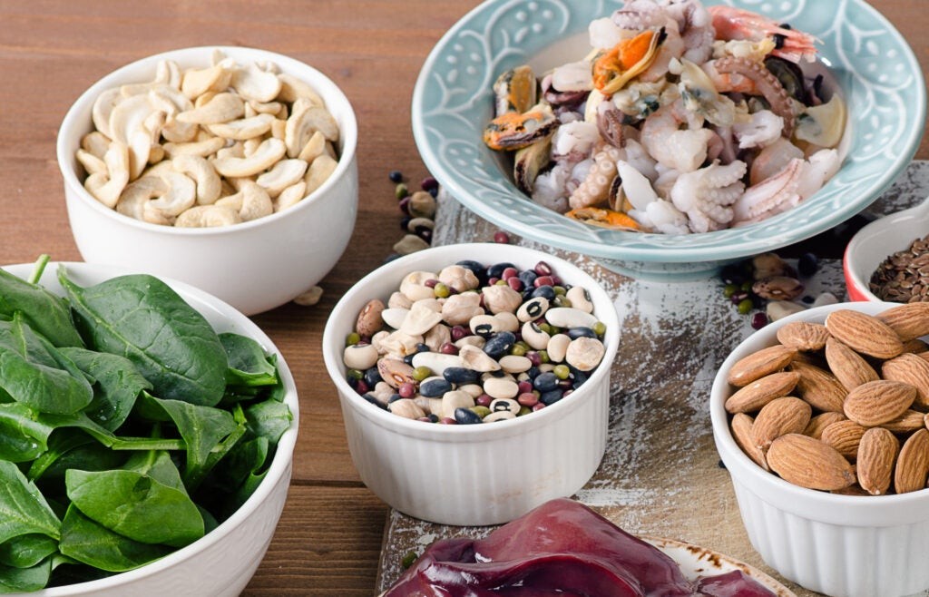 Close-up of assorted nuts, including hazelnuts, almonds, and pecans, displayed in a wooden bowl, showcasing their natural textures and colors