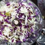 Sliced green and red cabbage in food processor bowl using slicer attachment.