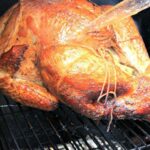 Whole turkey being basted on a smoker.