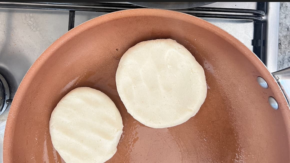 Venezuelan Arepas being prepared, showcasing their golden-brown exterior and diverse fillings